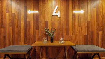 A wooden wall with a number '4' sign, a table with a vase and glass jars, and two cushioned benches.
