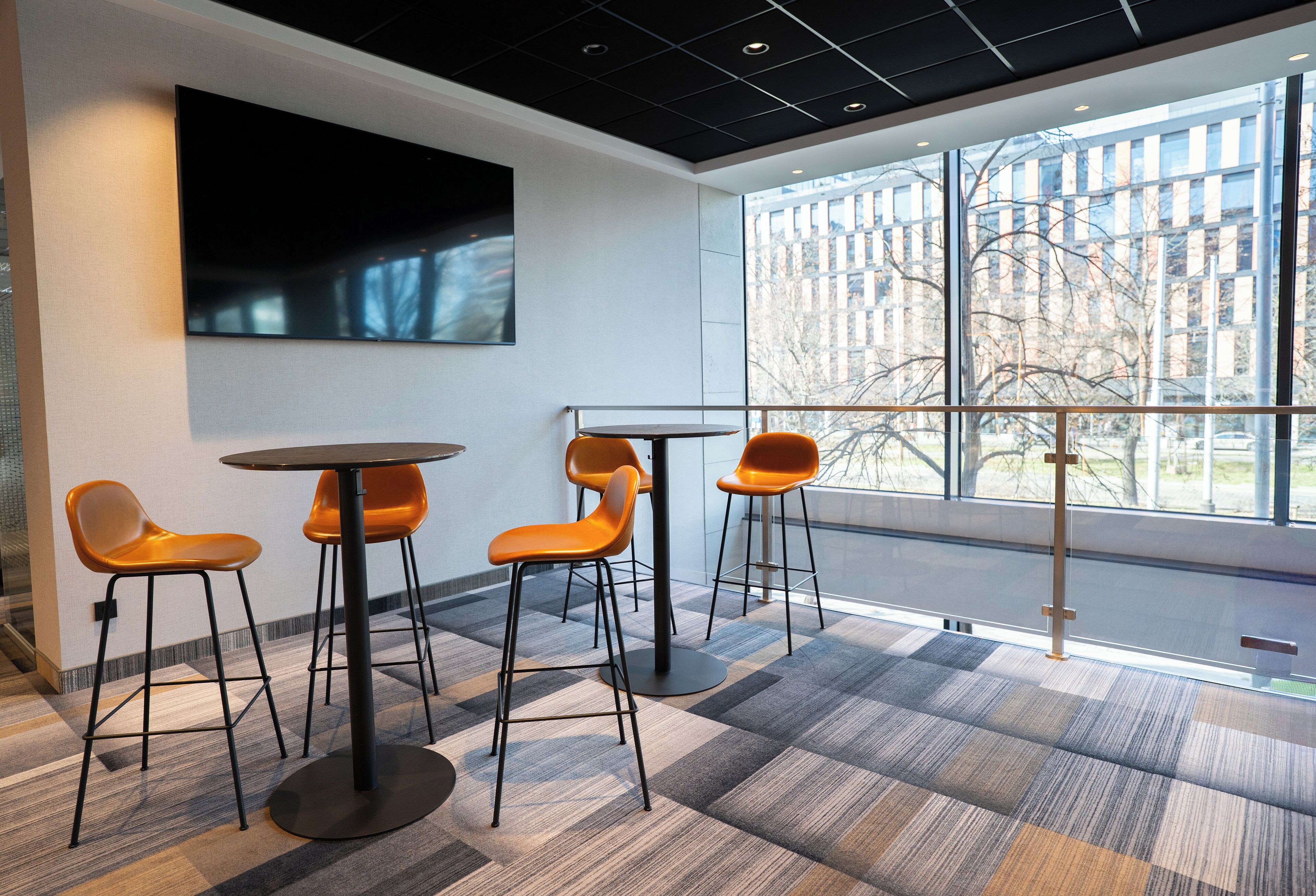 A modern interior with a large window, a flat-screen TV, and a bar area with stools.