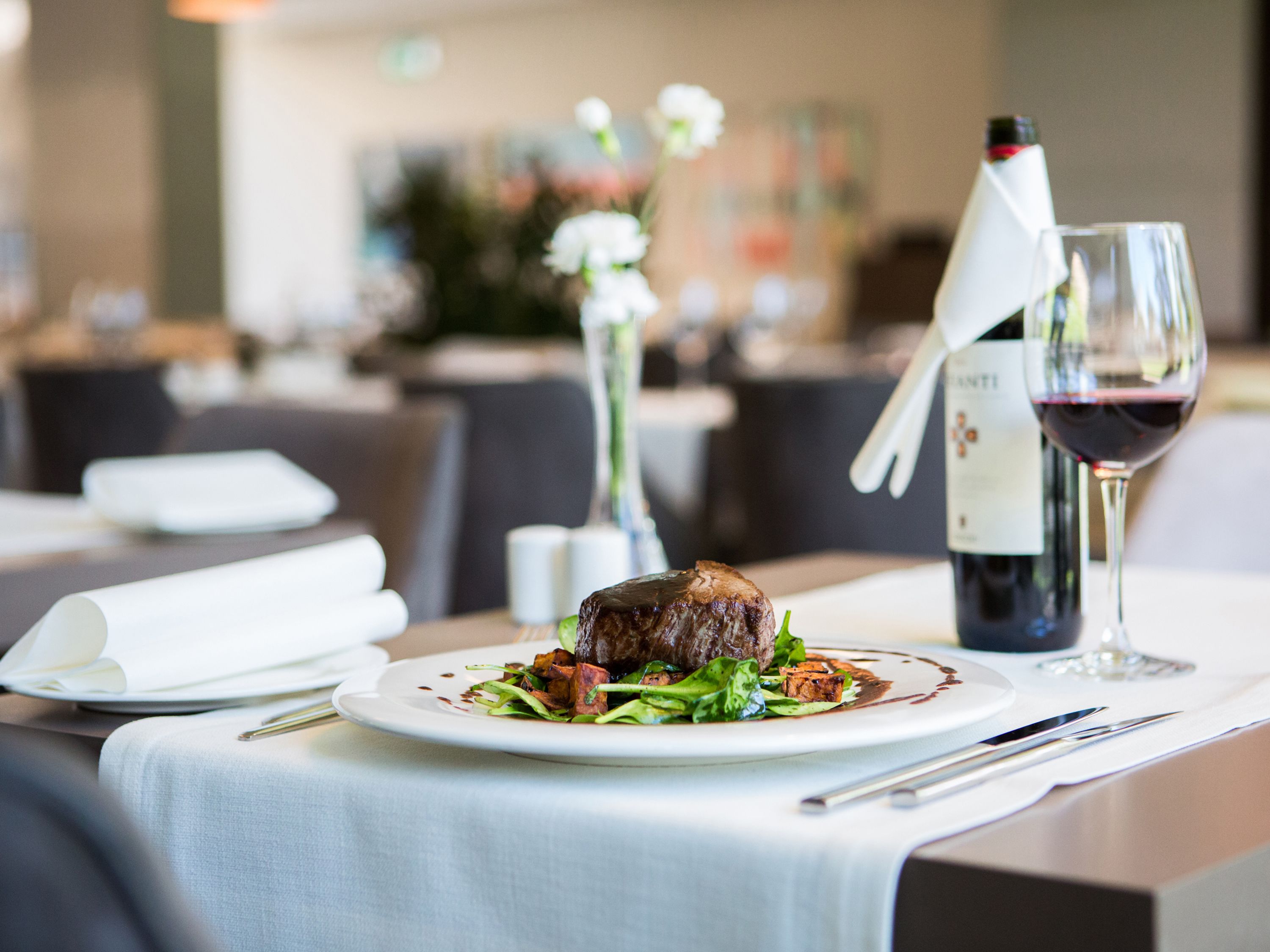 Une table à manger avec une assiette de nourriture, une bouteille de vin et un verre de vin.