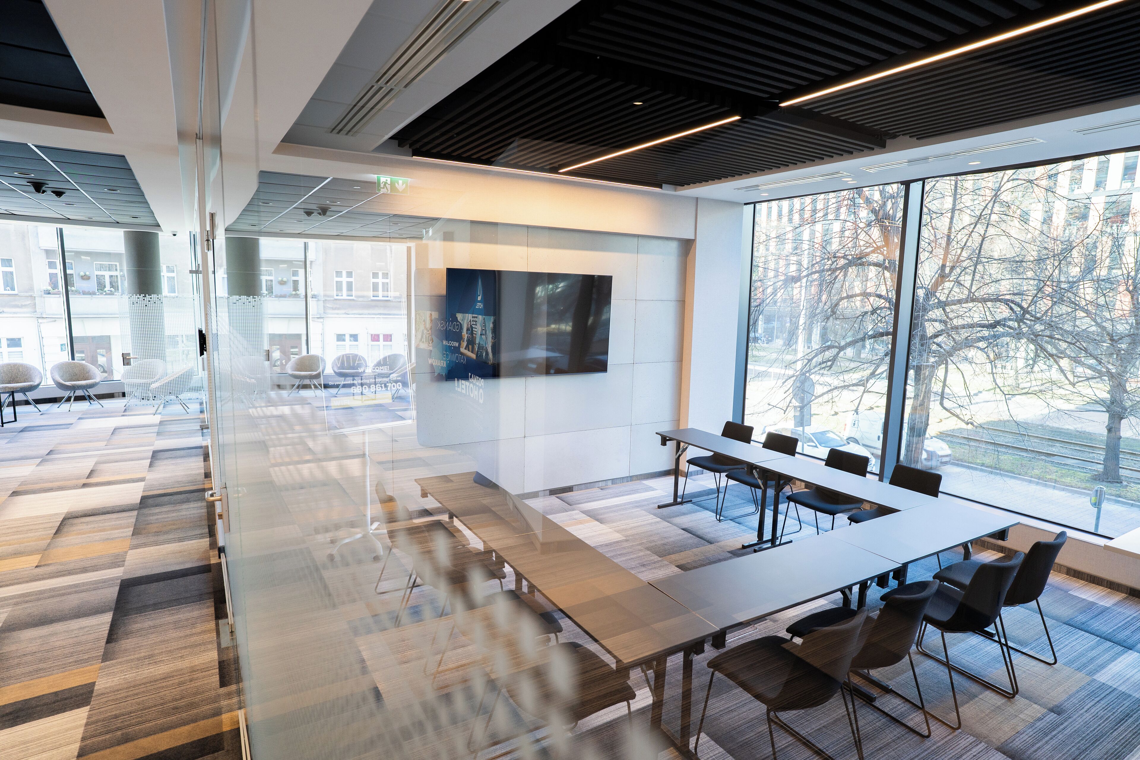 Uma sala de conferência moderna com uma mesa comprida, cadeiras e grandes janelas com vista para a cidade.