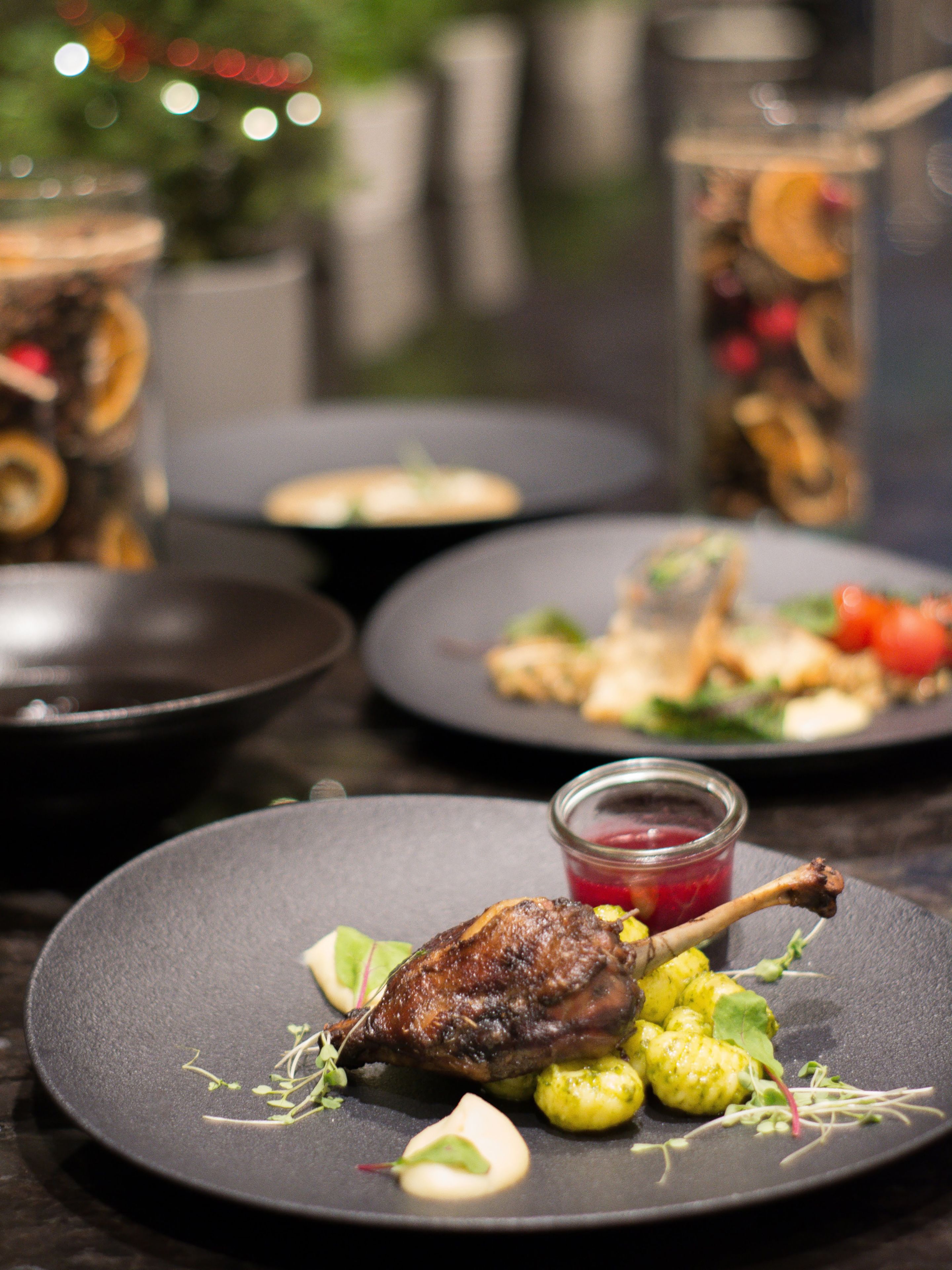 Una mesa de comedor con platos de comida, incluyendo un muslo de pato asado y verduras.