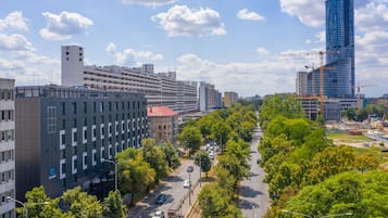 A modern urban street with buildings, trees, and a clear sky.