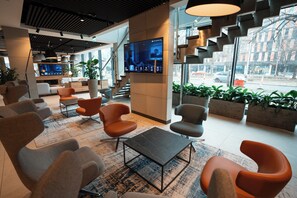 A modern lobby with seating areas, a large digital screen, and potted plants. - Q Hotel Plus Wroclaw (Wroclaw)