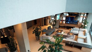 A modern living area with a sofa set, a coffee table, and a TV. There are potted plants and a staircase leading to another level. - Q Hotel Plus Wroclaw (Wroclaw)