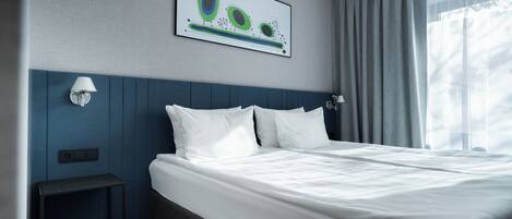 Una habitación de hotel moderna con una cama bien hecha, una obra de arte en la pared y una ventana con cortinas.
