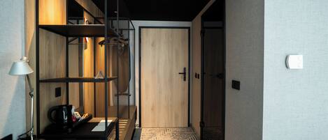 Habitación de hotel con puerta de madera, escritorio con lámpara y alfombra estampada.