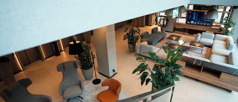 A modern hotel lobby with a seating area, a TV, and a staircase.