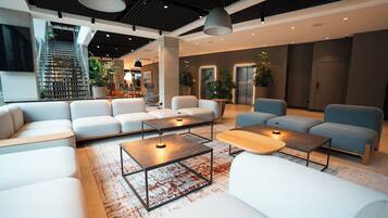 Eine moderne Lobby mit Treppe, Sitzbereichen und einer Rezeption.