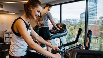 A gym with treadmills and a large window offering a city view.
