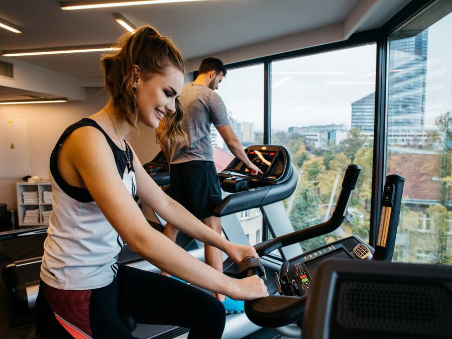 A gym with treadmills and a large window offering a city view.