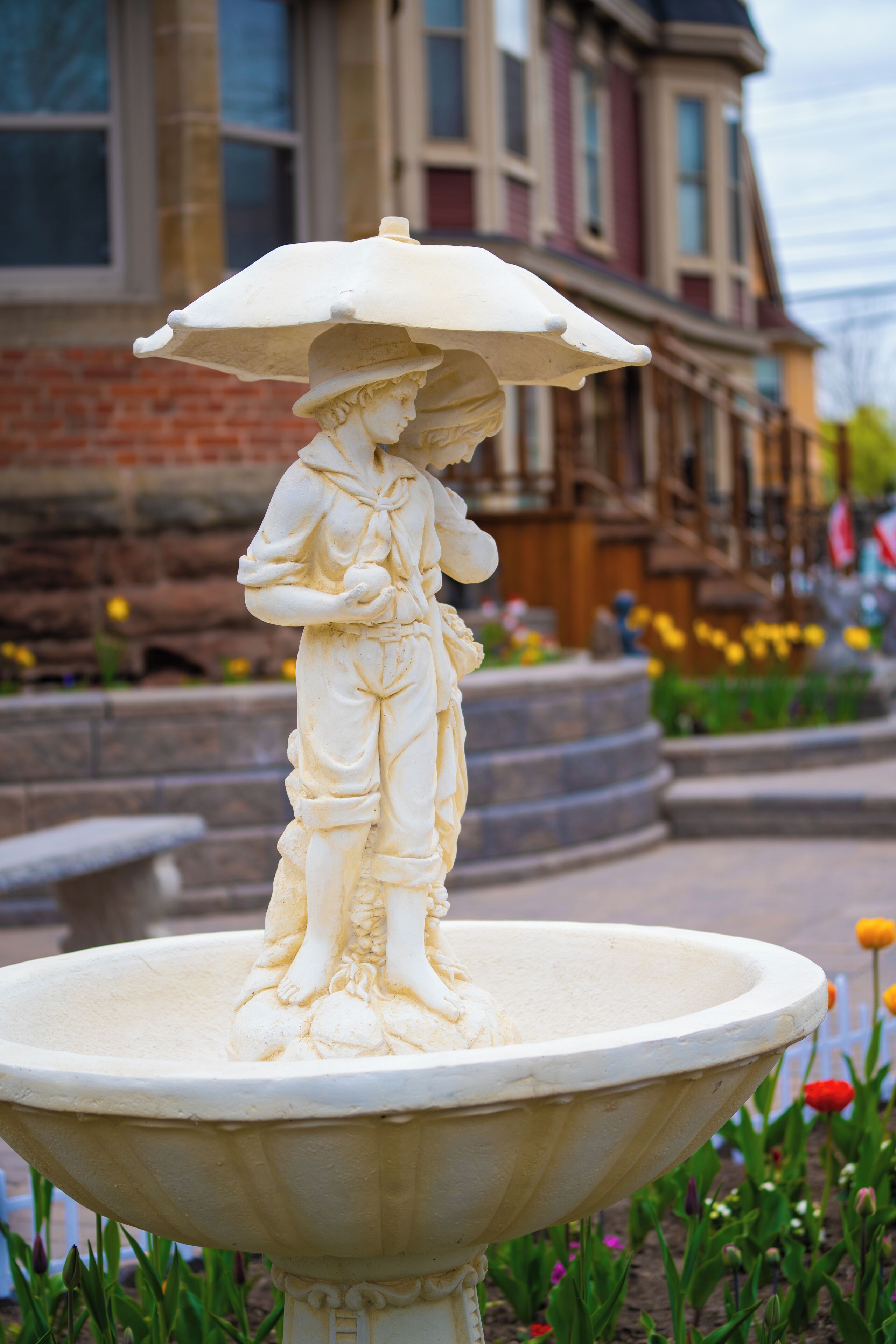 A statue of a person with an umbrella on a pedestal in an outdoor setting.