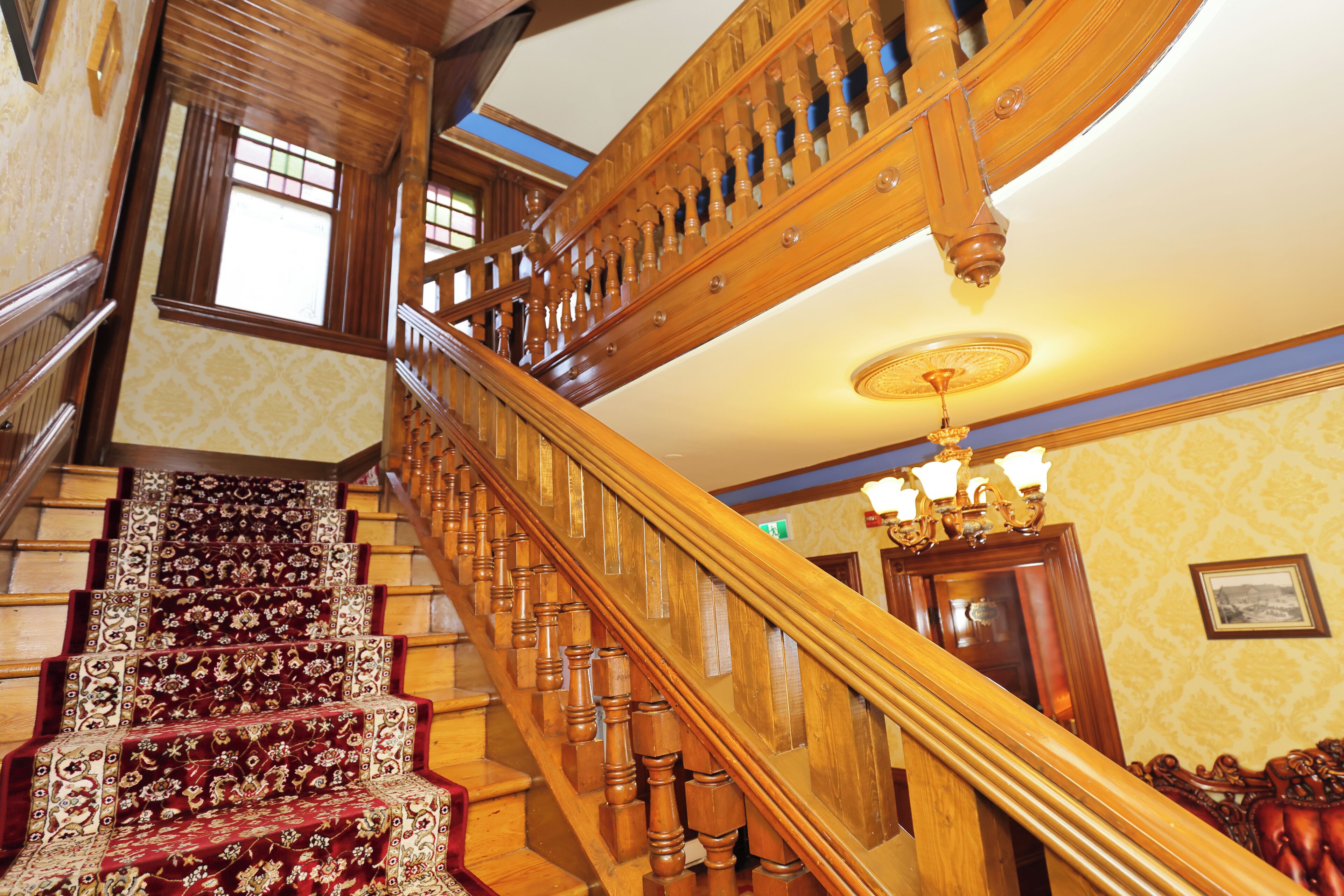 A grand staircase with ornate woodwork and a red carpet.