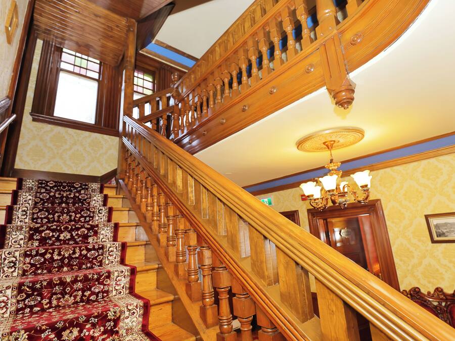 A grand staircase with ornate woodwork and a red carpet.
