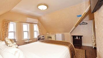 A hotel room with a large bed, a desk, a wardrobe, and a television.