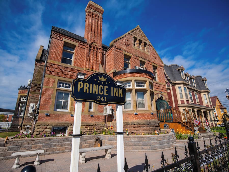 Un edificio de ladrillo con un letrero que dice "Prince Inn 241" y un banco de piedra en la fachada.