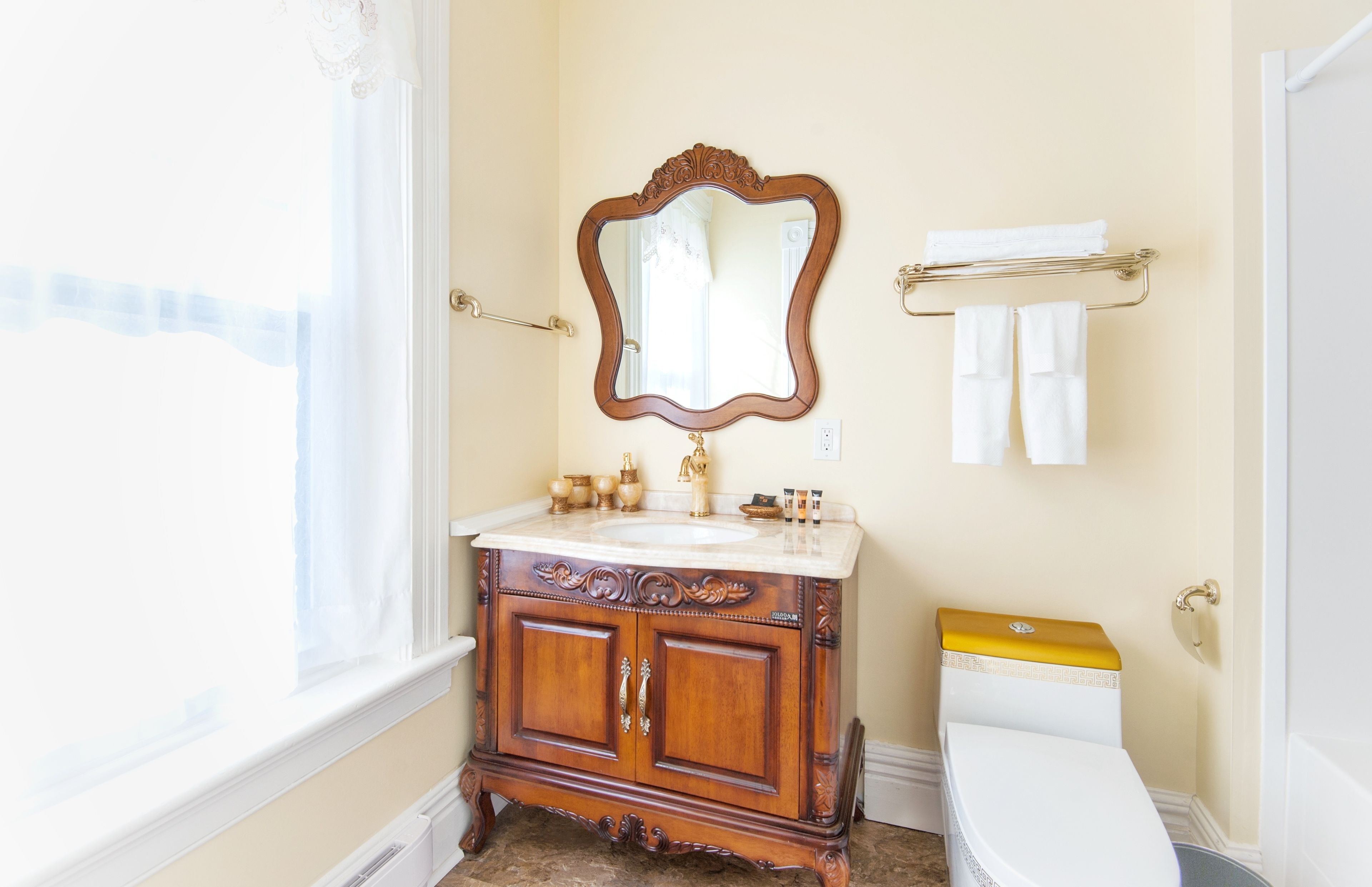 A bathroom with a wooden vanity, a white toilet, and a mirror.