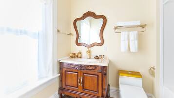 A bathroom with a wooden vanity, a white toilet, and a mirror.