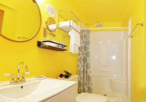 Un baño con lavamanos, espejo, toallero, cortina de ducha e inodoro.