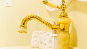 A bathroom with a gold faucet, a mirror, and a tissue box.