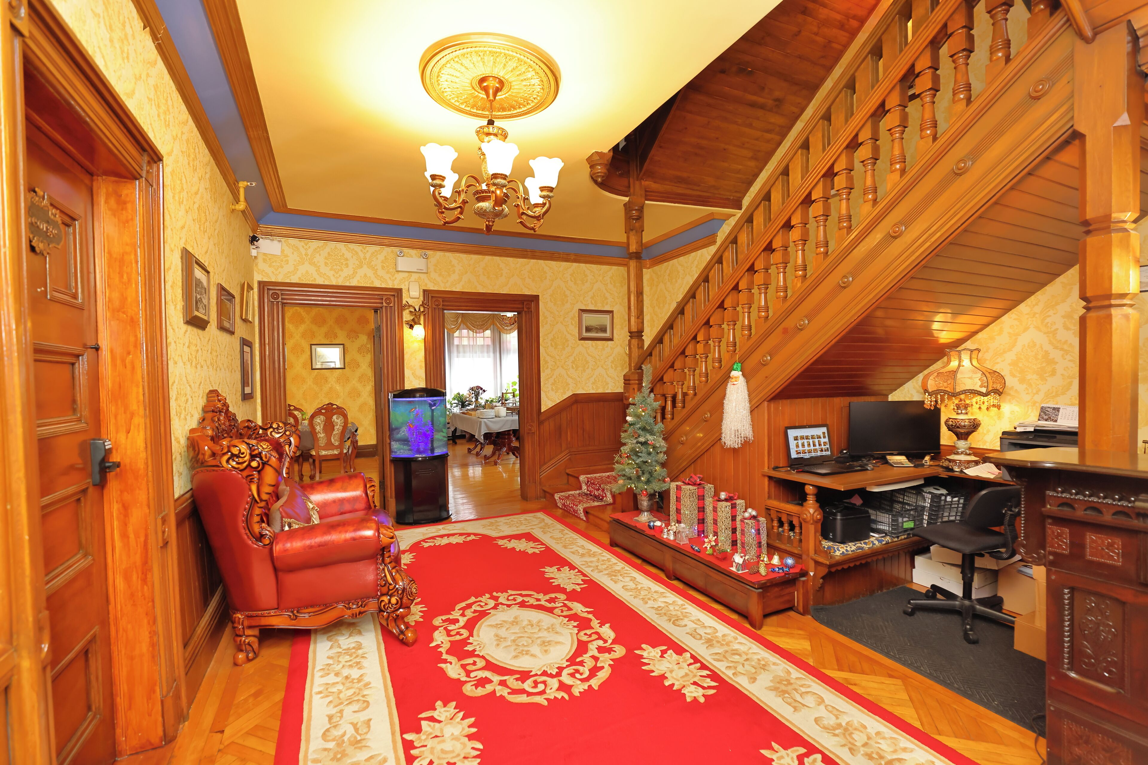 A spacious living room with a red carpet, wooden staircase, and a television.