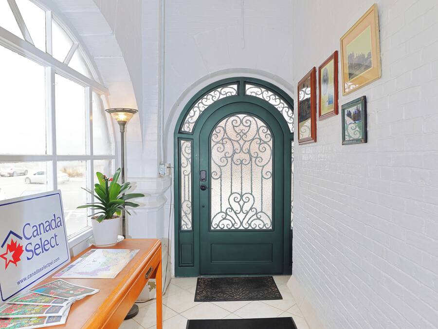A reception area with a Canada Select sign, a desk with brochures, a potted plant, a green door with decorative glass, and framed pictures on the wall.