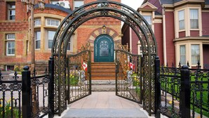 A wrought iron gate leading to a building with a green door and a stone staircase.