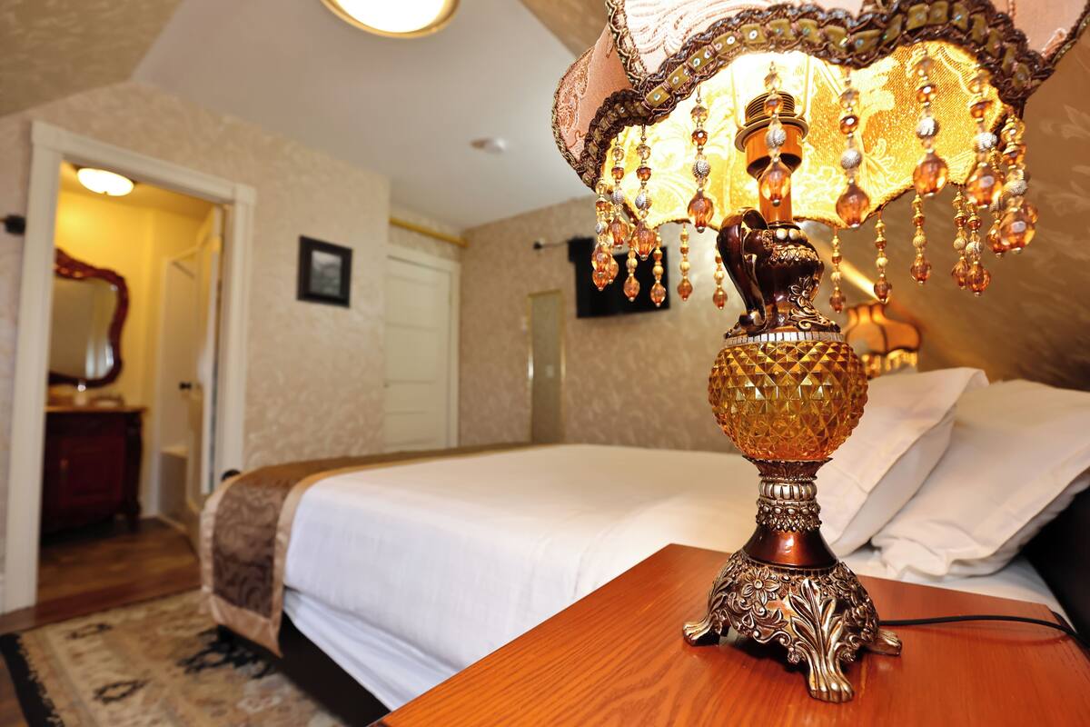 A bedroom with a large bed, a wooden nightstand, and a decorative lamp.