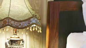 A wooden nightstand with a green lamp, a book, and a white bed with a wooden headboard.