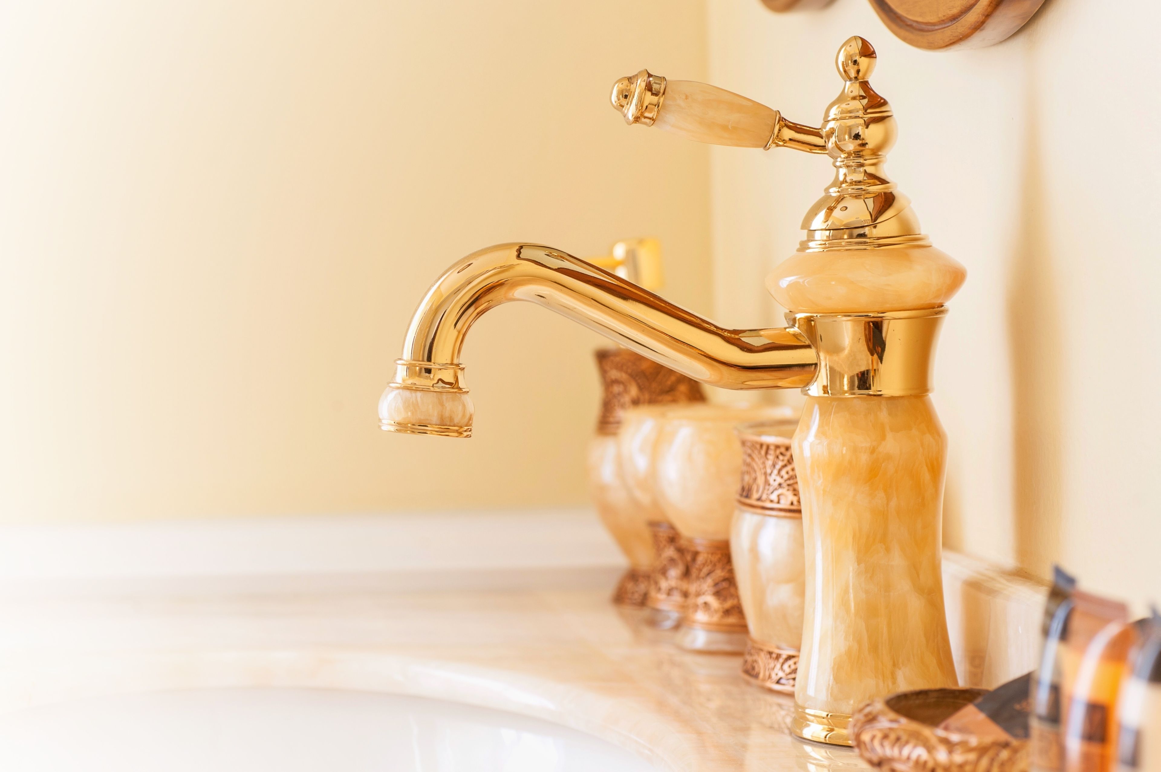 Un baño con grifo dorado y encimera de mármol.