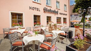 Un hôtel doté d’un espace extérieur aménagé avec des tables, des chaises et des arrangements floraux.