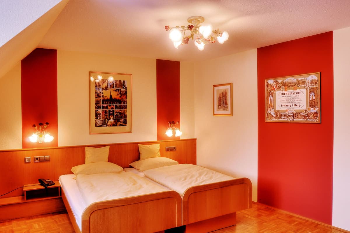 Habitación de hotel con una cama doble, una mesita de noche con teléfono y dos lámparas de pared.