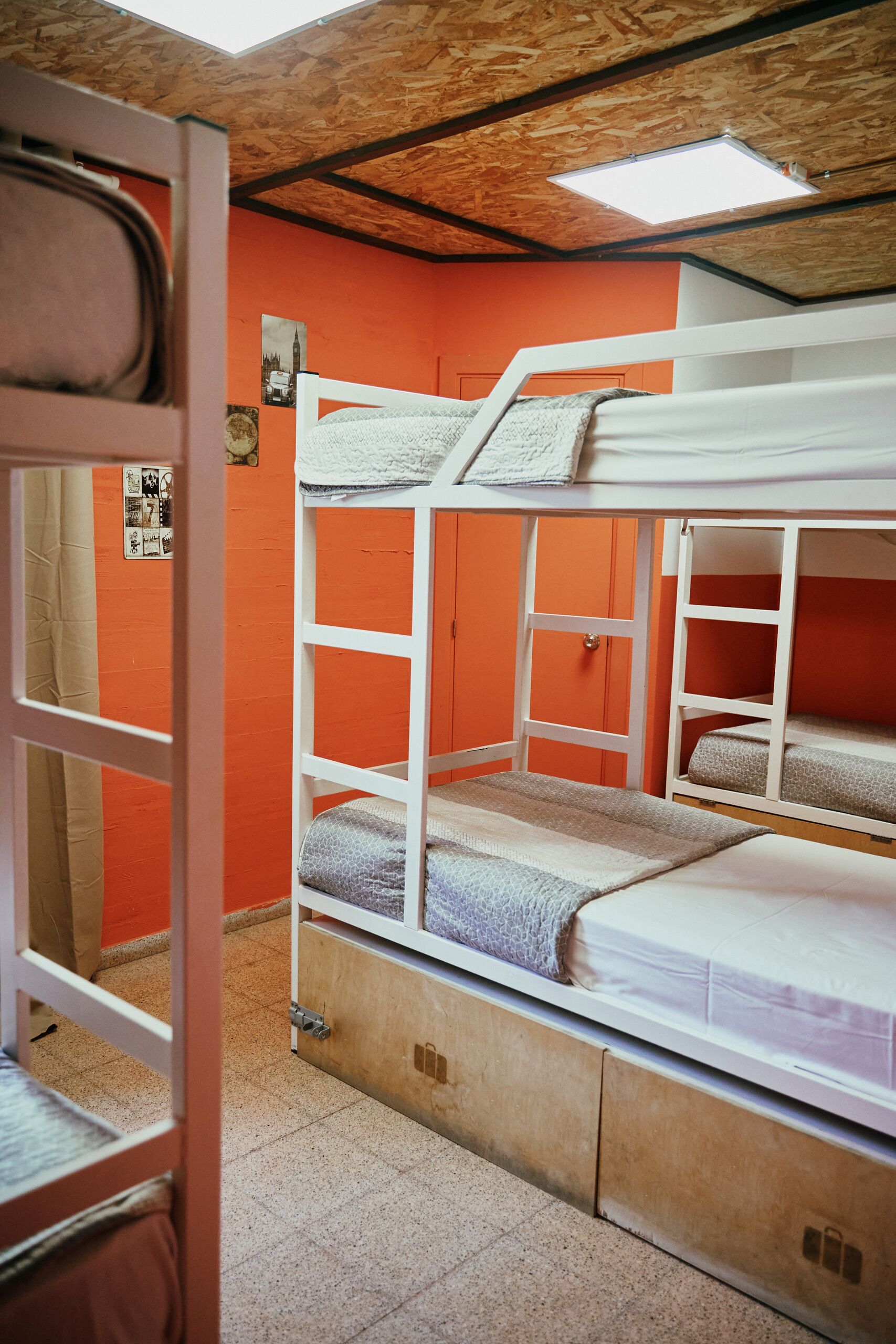 A bunk bed room with orange walls, wooden ceiling, and a visible door frame.