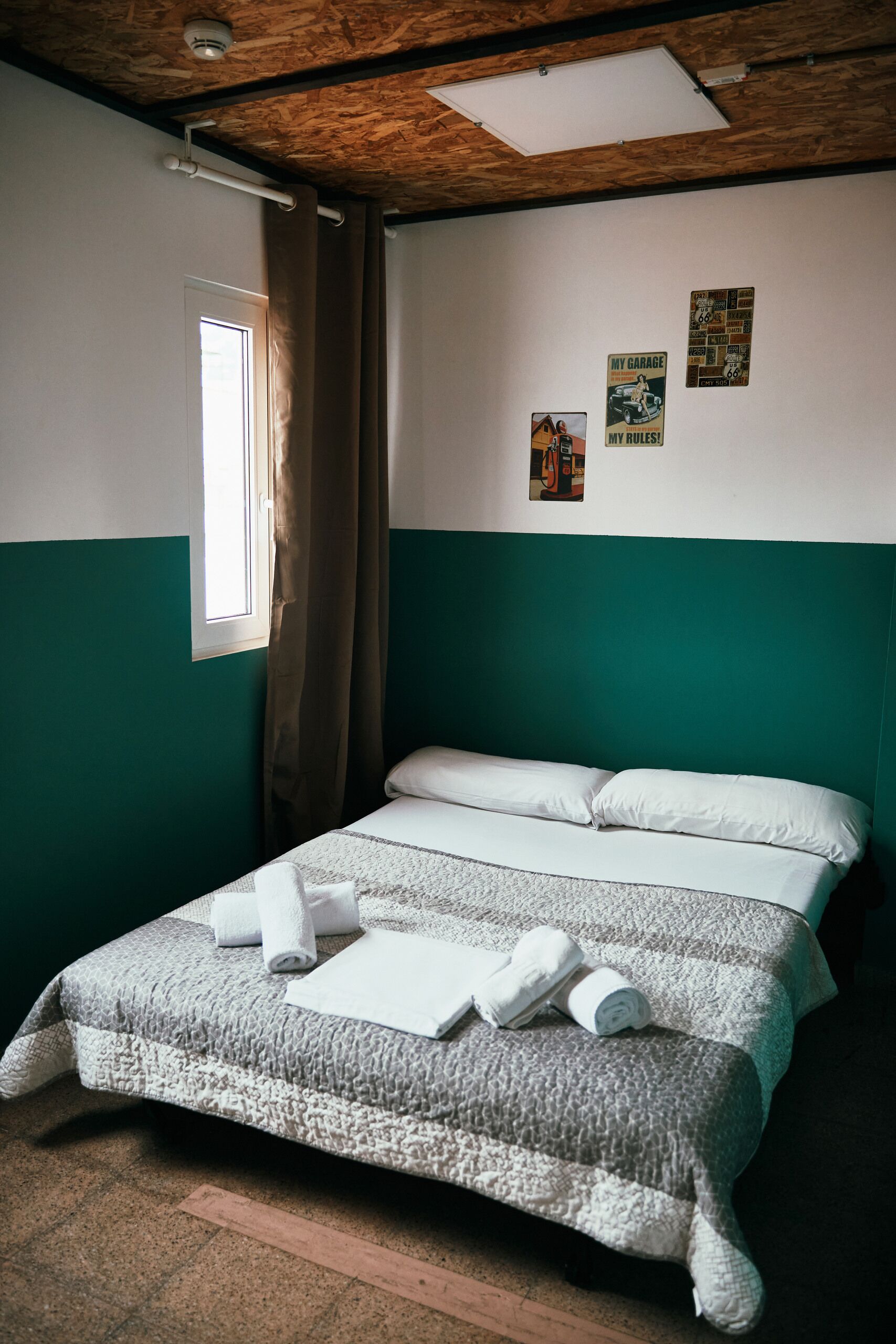 A room with a bed, a window with curtains, and wall decorations.