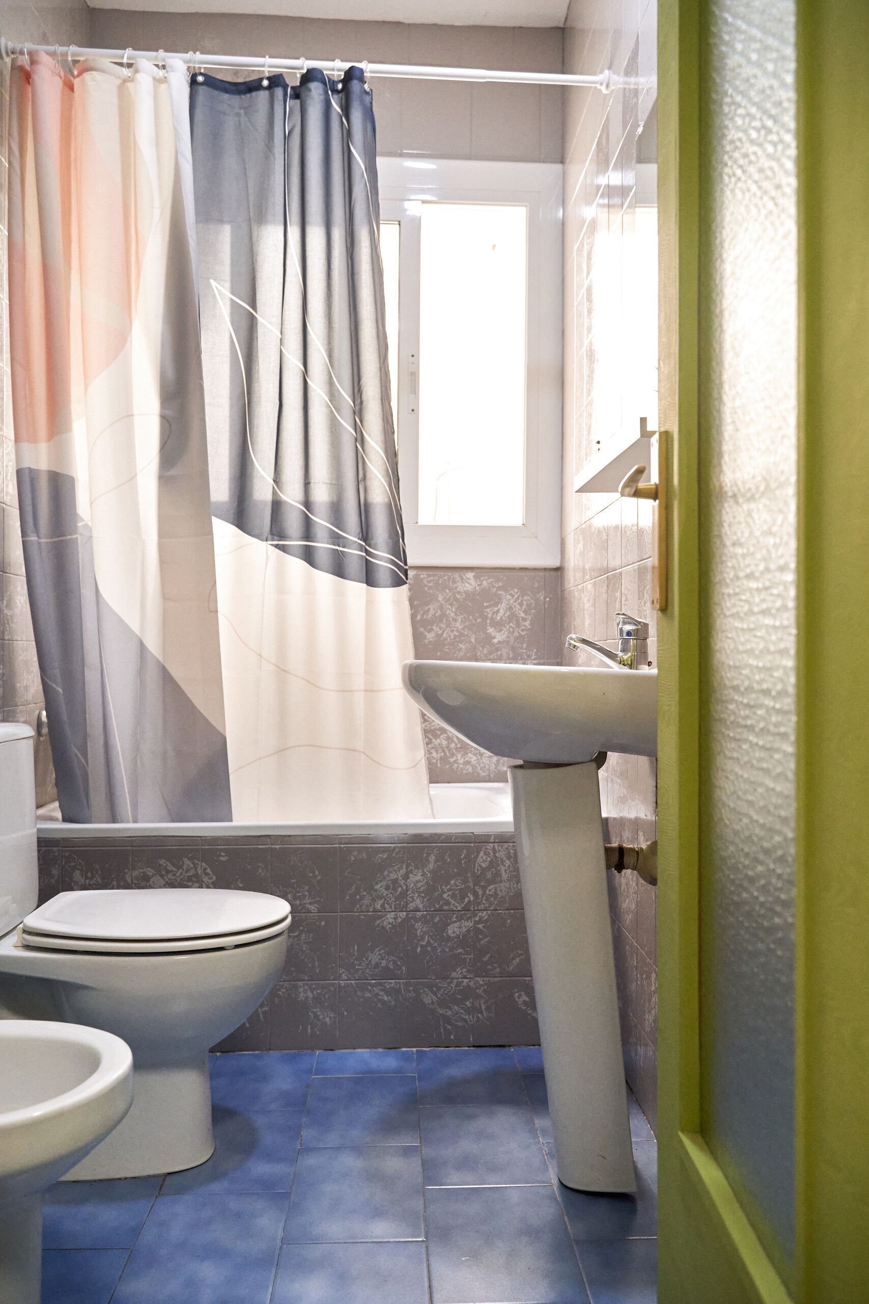 Un baño con inodoro, lavamanos y cortina de ducha.