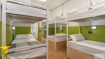 Une chambre de dortoir avec des lits superposés, des murs verts et une fleur sur le côté gauche.