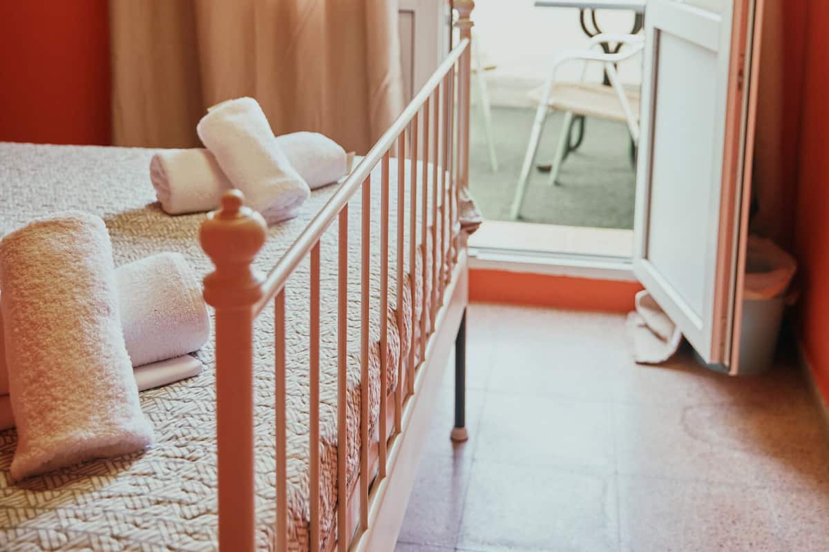 Een slaapkamer met een bed, handdoeken en een balkon met een tafel en stoel.