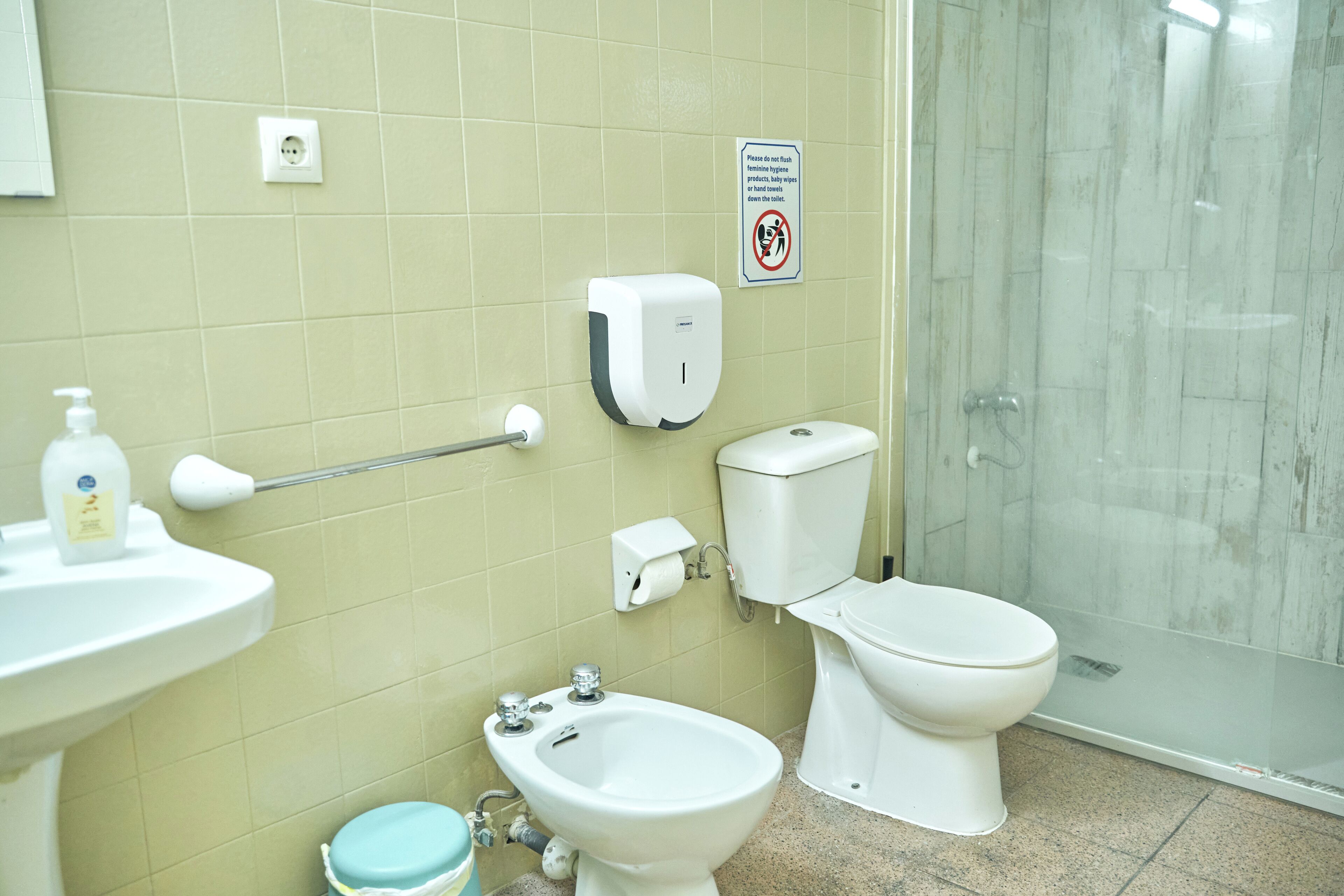 Un baño con inodoro, bidé, lavabo y secamanos.