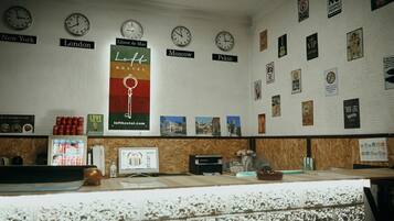 A reception desk with clocks labeled with city names, a poster for a hotel, and various wall decorations.