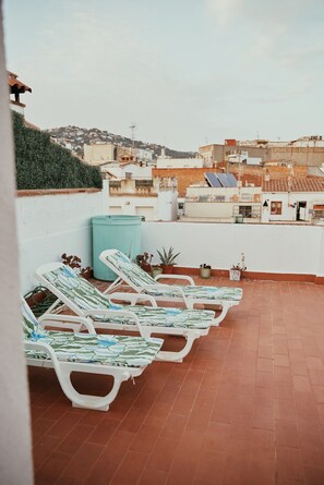 A rooftop terrace with several sun loungers, a trash bin, and potted plants. - Loft Hostal - Hostel (Lloret de Mar)