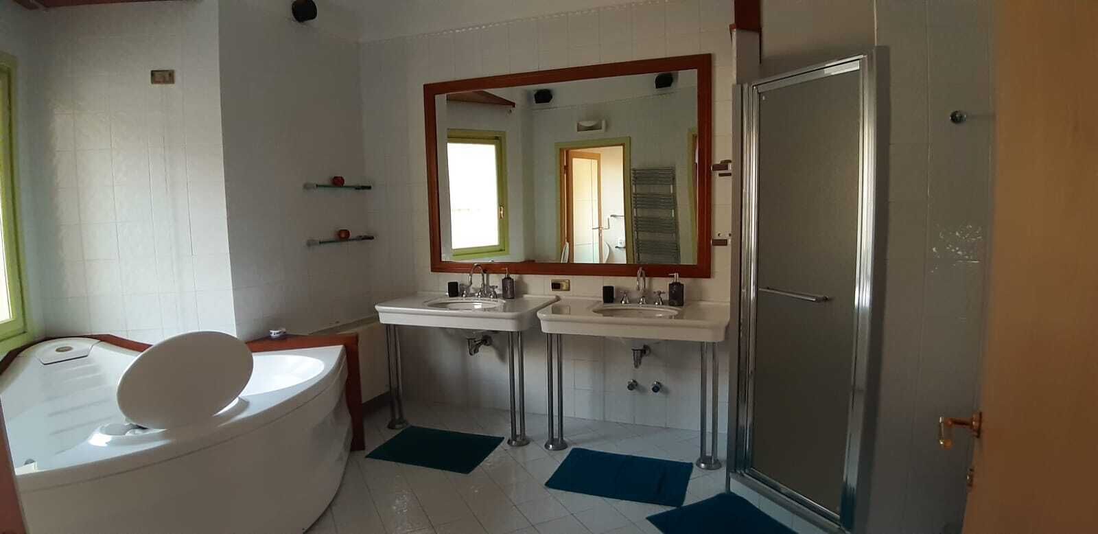 Ein Badezimmer mit einer Badewanne, zwei Waschbecken, einem Spiegel und einer Dusche.