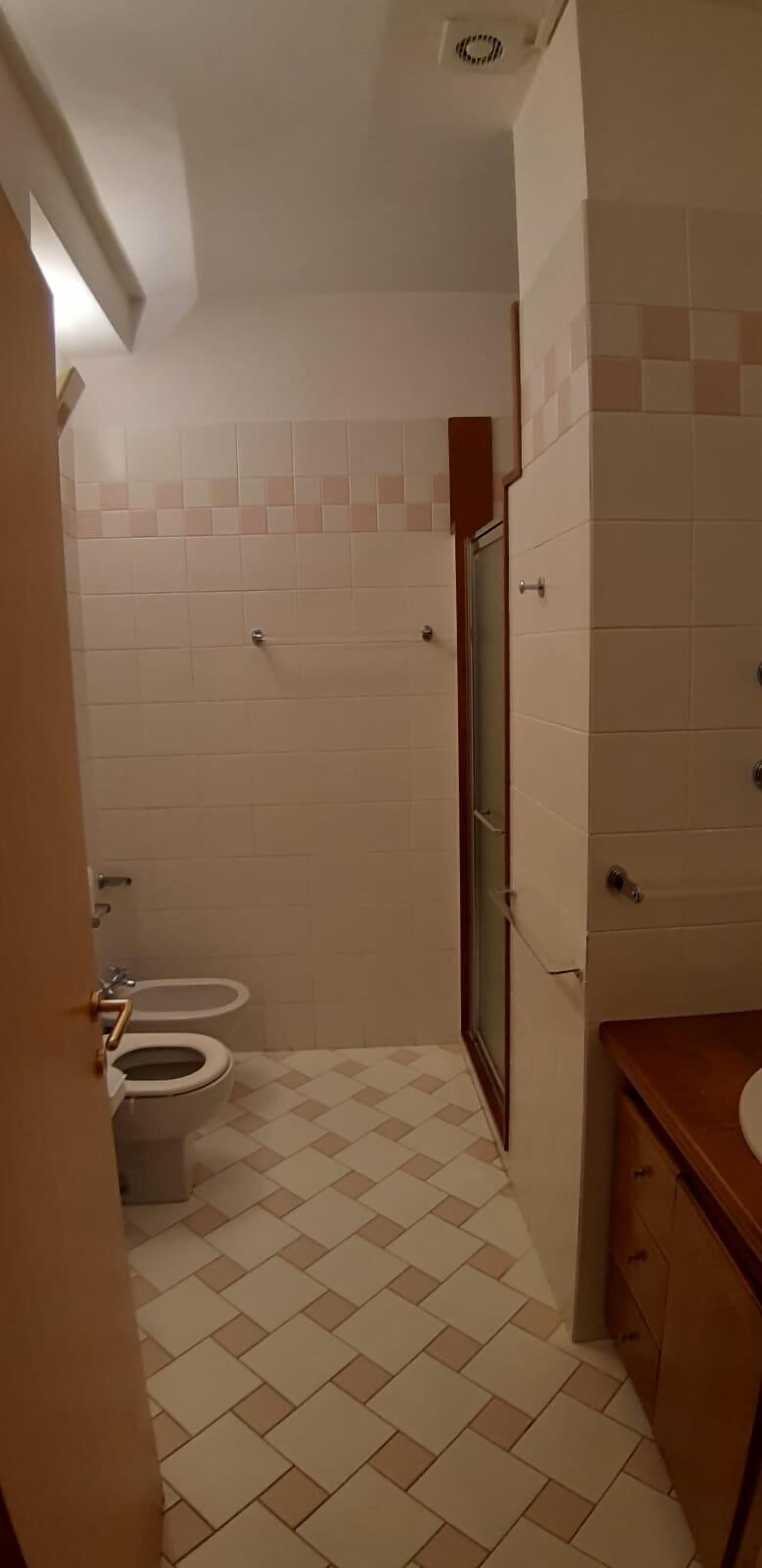 A small bathroom with a toilet, a shower, and a sink.