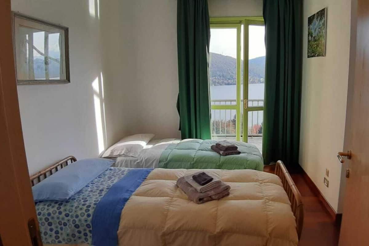 A hotel room with two beds, a view of a lake, and a door to the left.