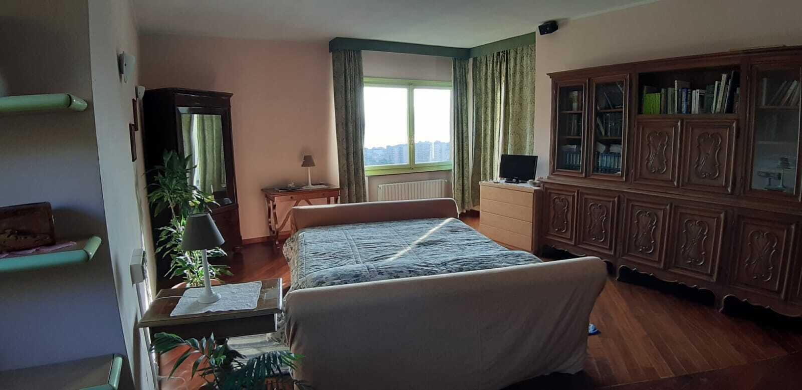 A bedroom with a bed, a wooden cabinet, a desk, and a window with curtains.
