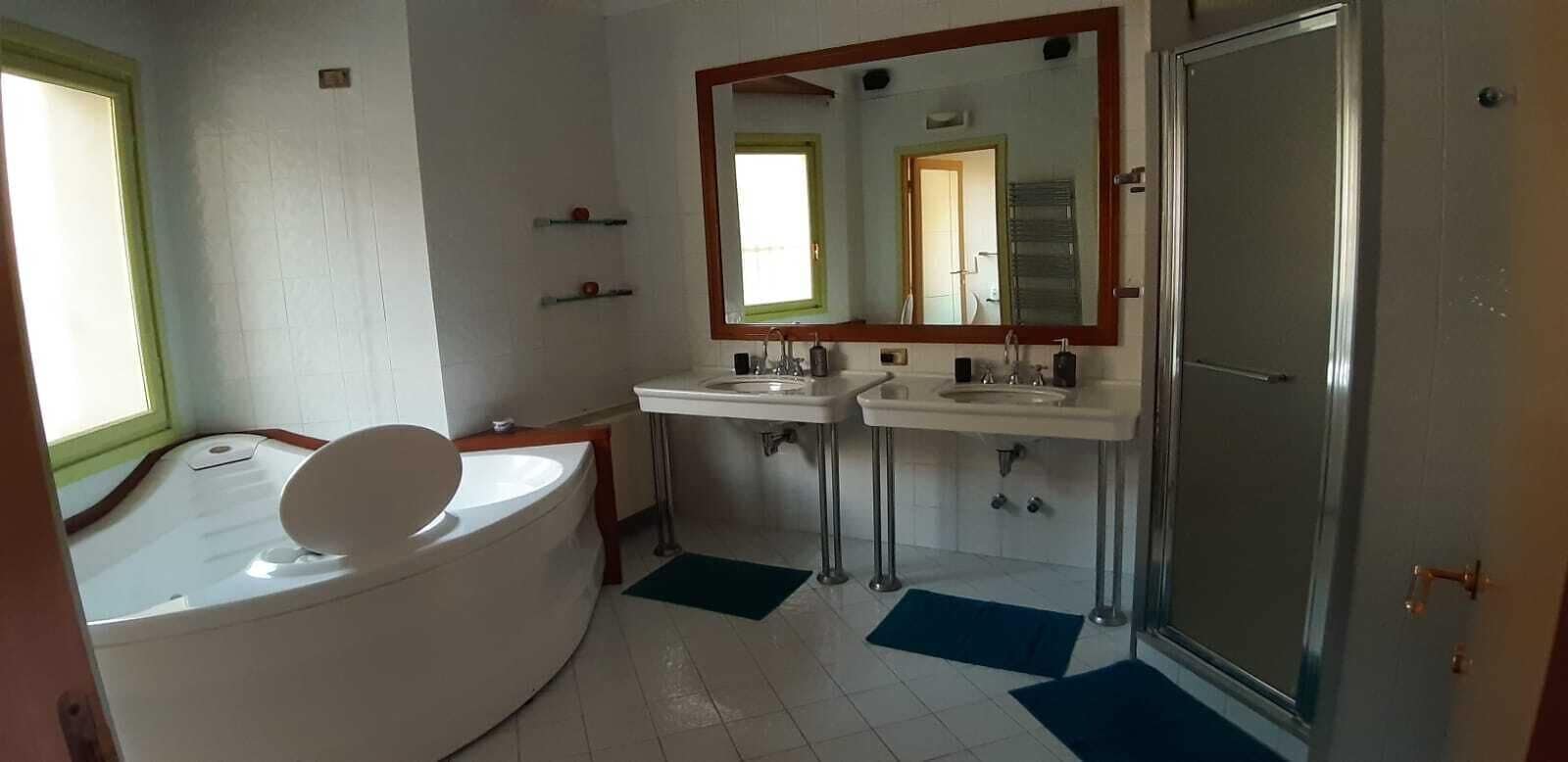A bathroom with a bathtub, two sinks, a large mirror, and a shower.
