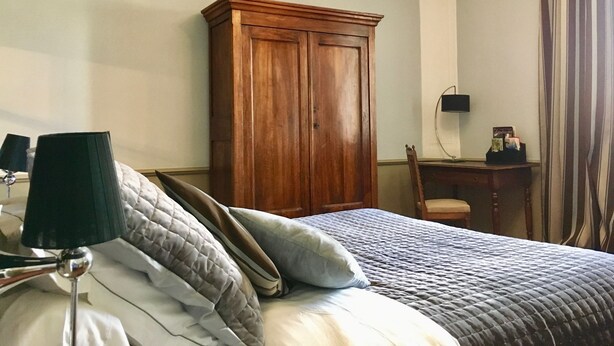 Un dormitorio con una cama, un armario de madera, un escritorio con silla y una lámpara.