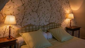 A bedroom with a checkered headboard, two bedside tables with lamps, and floral wallpaper.