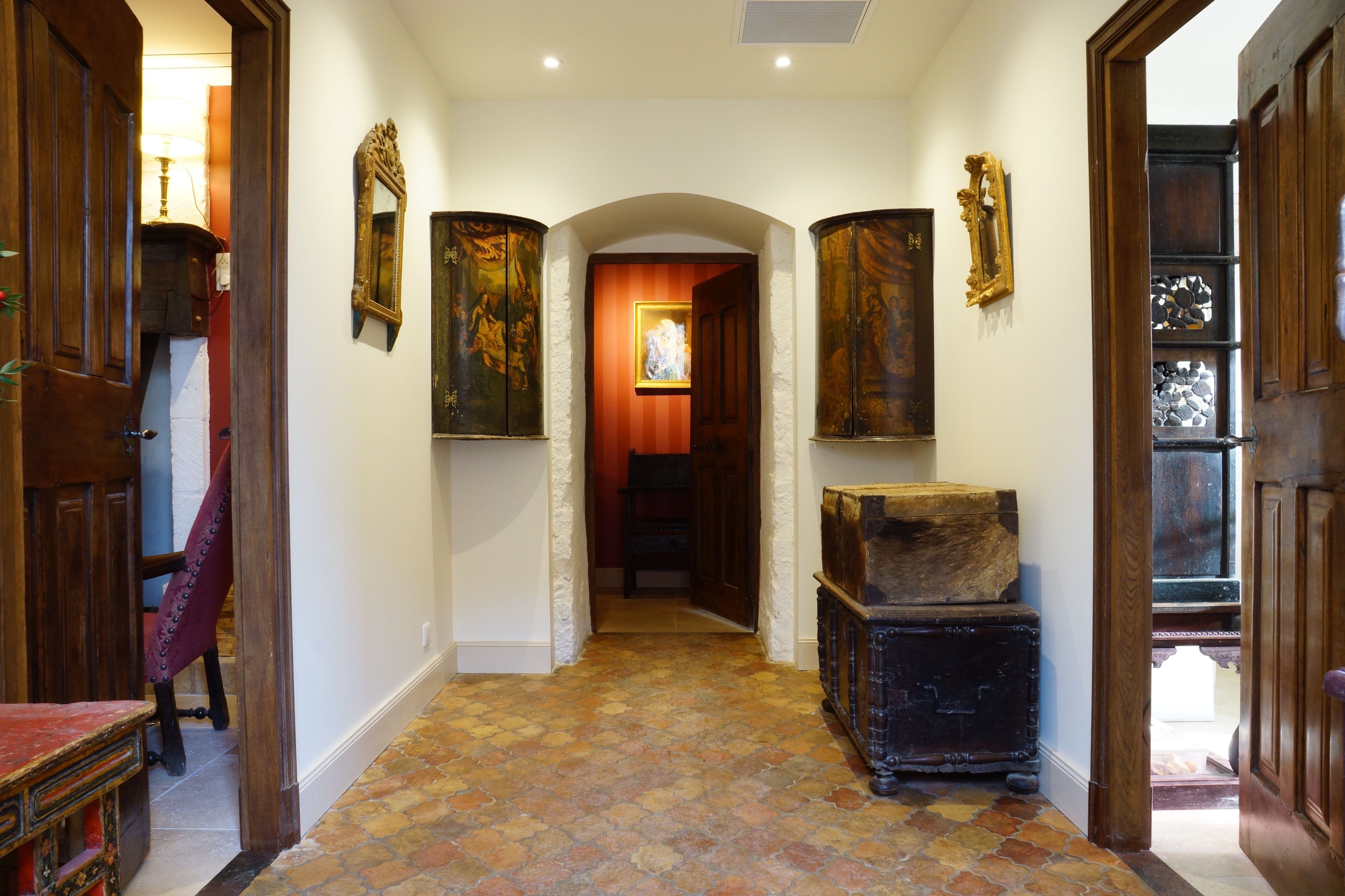 Un couloir doté d’un sol carrelé, de portes en bois et d’œuvres d’art encadrées accrochées aux murs.