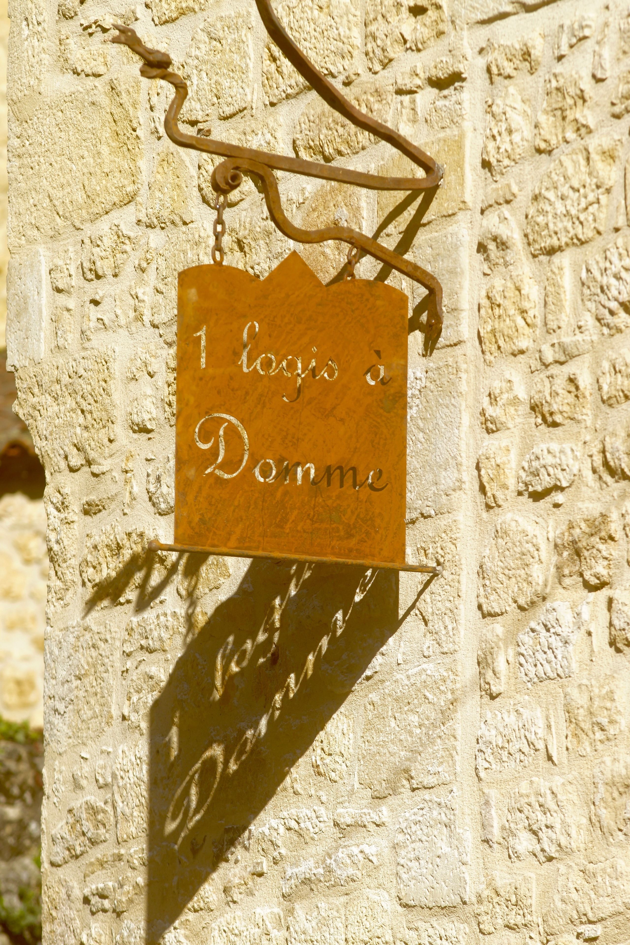 Un cartel con el texto '1 logis à Demme' fijado a una pared de piedra.