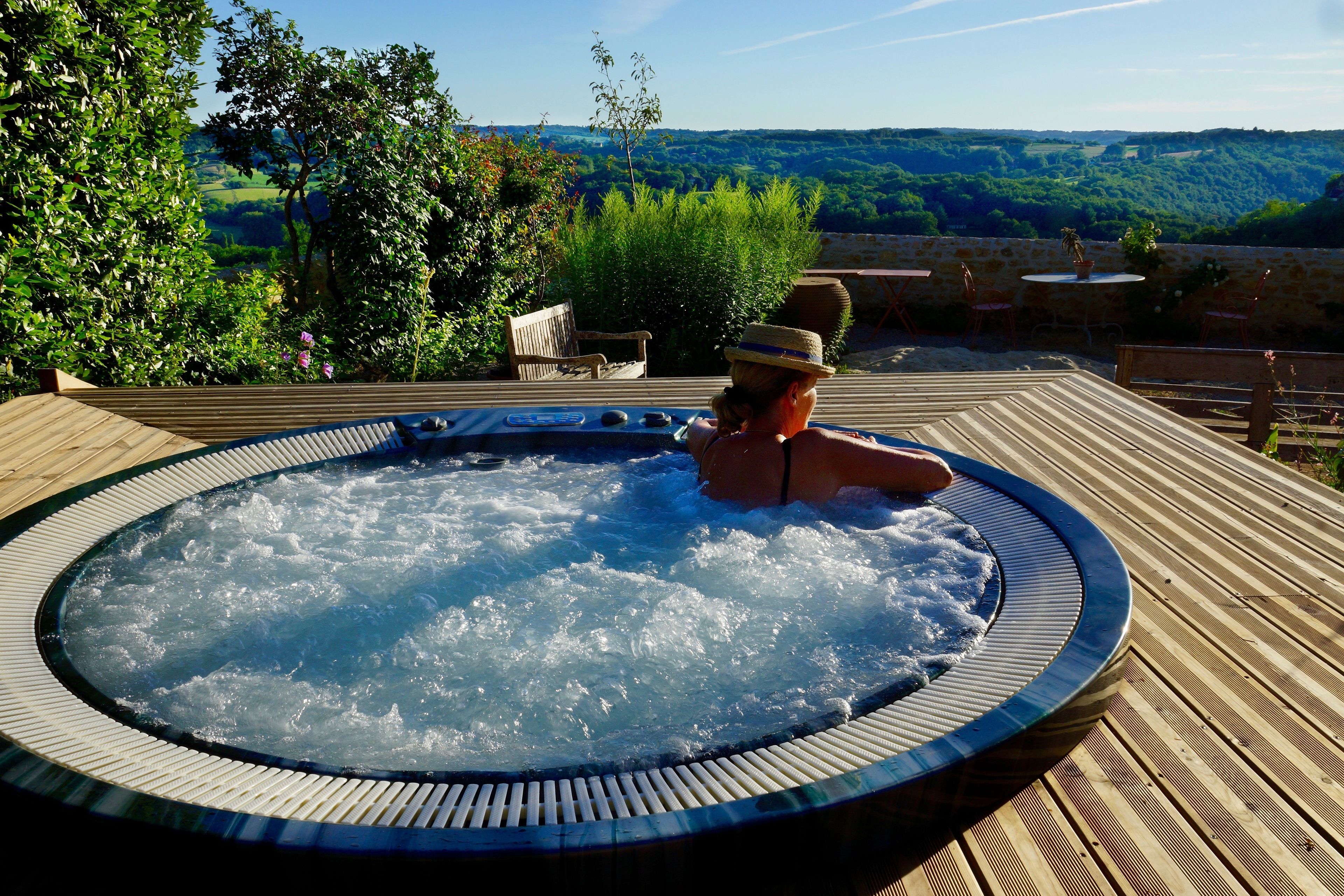 Un jacuzzi con terraza de madera y una vista panorámica de colinas.