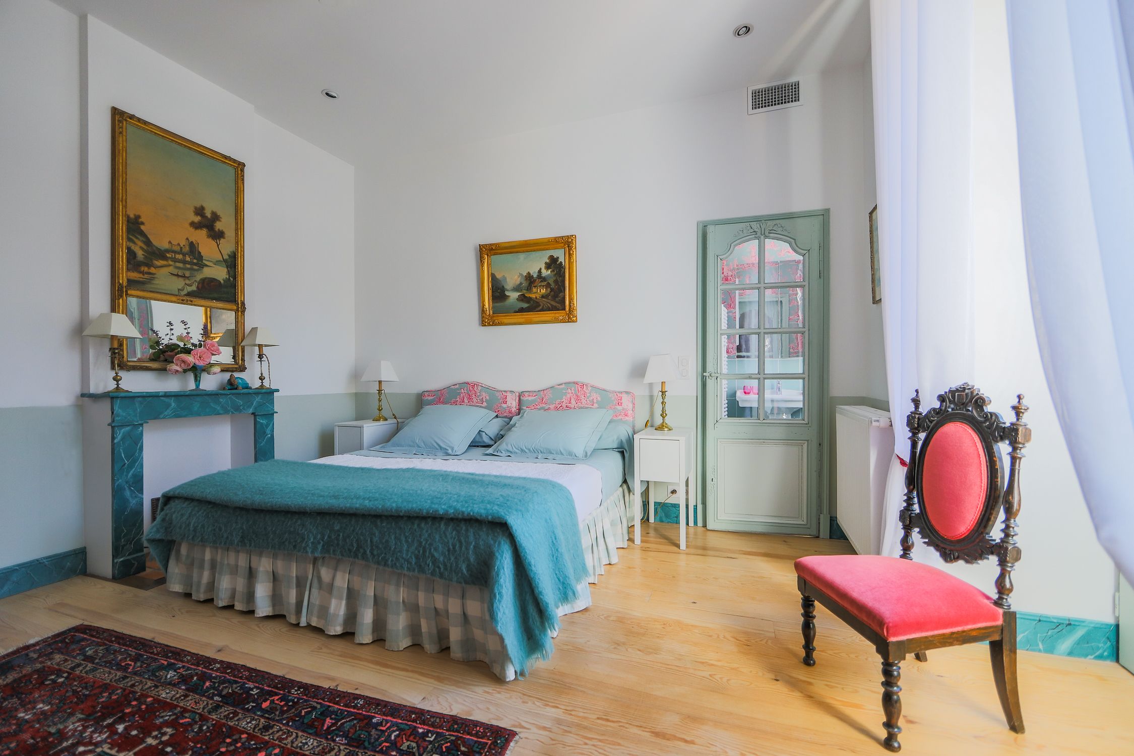 A bedroom with a bed, a chair, a dresser, and a door.